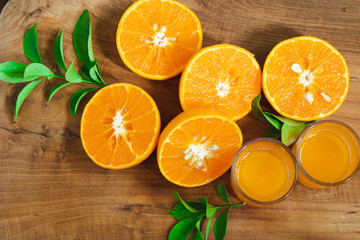 A piece of mandarin orange fruit sliced with leaves on the golden teak floor And two orange juice glasses. As a background image.