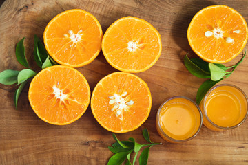 A piece of mandarin orange fruit sliced with leaves on the golden teak floor And two orange juice glasses. As a background image.