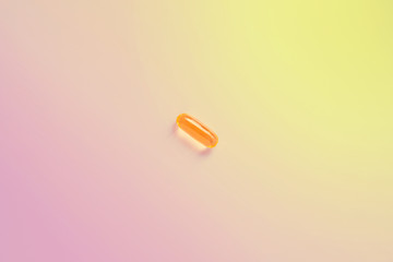 yellow omega 3 pill on a colored background.