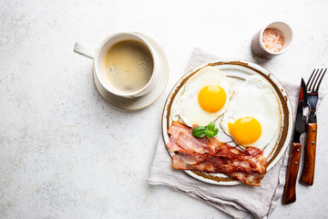 Fried eggs and bacon for breakfast on a plate, top view, copyspace