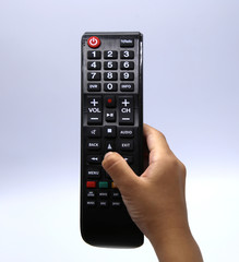 Woman’s hand holding black multimedia television remote control isolated on white background.