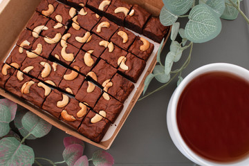 Homemade brownies using real butter, no baking powder, mixed with green, red raisins, chopped nuts, placed on a wooden tray With some ingredients And partially decorated with leaves.