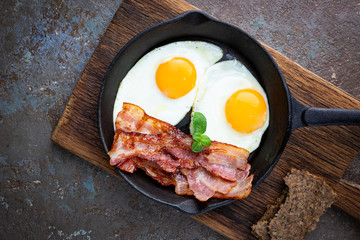 Fried eggs and bacon for breakfast on a frying pan, top view, copyspace