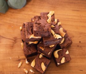 Homemade brownies using real butter, no baking powder, mixed with green, red raisins, chopped nuts, placed on a wooden tray With some ingredients And partially decorated with leaves