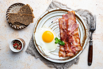 Fried eggs and bacon for breakfast on a plate, top view, copyspace