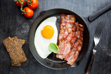 Fried eggs and bacon for breakfast on a frying pan, top view, copyspace