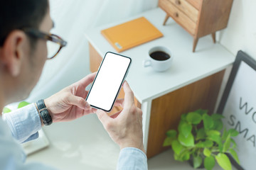 Mockup image blank white screen cell phone.men hand holding texting using mobile on desk at home office.background empty space for advertise text.people contact marketing business,technology 