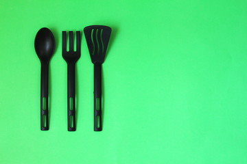 black fork and spoon on green background.