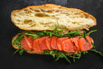 fish sandwich and greens, Smorrebrod (salted salmon, croissant, bread, arugula and other ingredients) menu concept. food background. top view. copy space