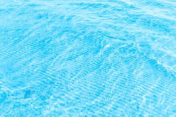 Fototapeta na wymiar Blue transparent sea water near the beach texture background. clear water surface with slight waves and glare on a sunny day. sea ​​vacation