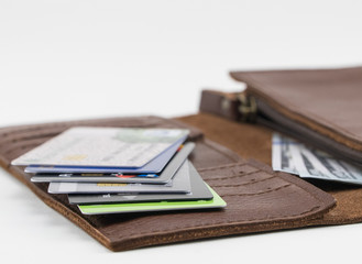 Brown wallet with credit cards and hundred dollar bills on white background