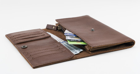 Brown wallet with credit cards and hundred dollar bills on white background