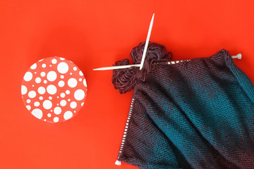knitted sweater with white skewers on the red background. And gitf box