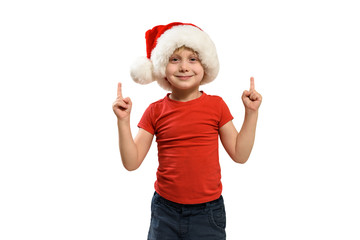 Blond boy in Santa hat points fingers up. Isolate
