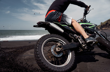  Man ride on the motorbike at the ocean black sand beach