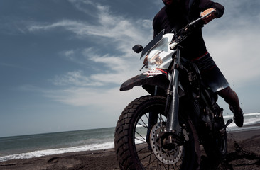 Fototapeta na wymiar Man ride on the motorbike at the ocean black sand beach