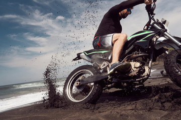  Man ride on the motorbike at the ocean black sand beach