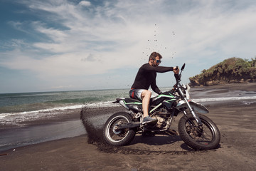Fototapeta na wymiar Man ride on the motorbike at the ocean black sand beach