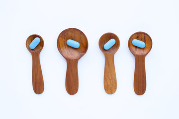 Medical blue pills with he wooden spoon on white background.
