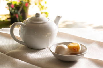 side view white pot of hot coffee  served with two small mooncake on table with vintage tone. Break times concept.