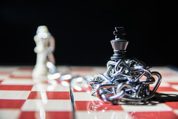 Imprisoned and caught. Black king is surround with chains and white king is also seen on the chess...