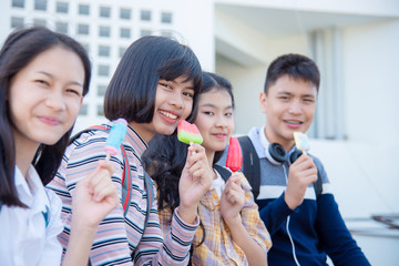 Beautiful asian teenage woman sitting and eating ice-cream with friends.