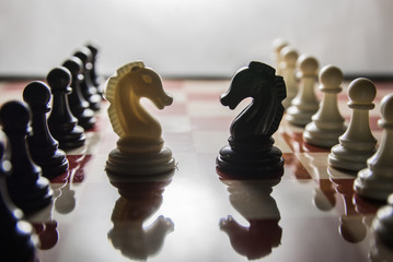 Symbolic contrast shot on chess board. White knight with black pawn army vs black knight and white pawn army face to face © GlobalReporter