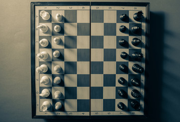 Top angle view of vintage look of chess with dramatic light creating shadows. White and black. White vs black