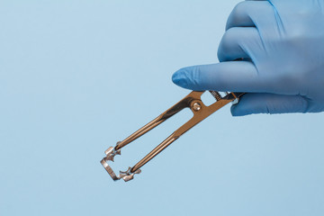 Dentist's hand in glove with dental tongs and clasp.