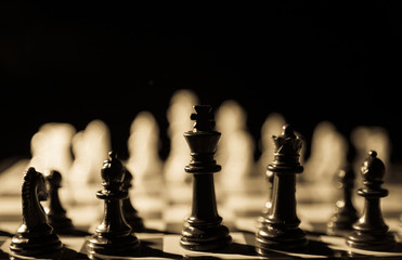 Vintage look of chess king and pieces in silhouette with white chess pieces in background