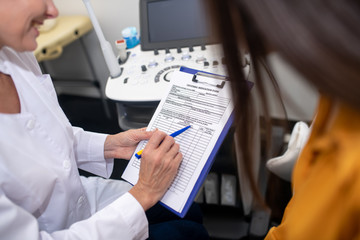 Blond doctor in white robe showing the assignment sheet to the patient