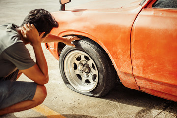 A man headache when car breakdown and wheel flat tire in parking