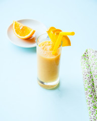 Organic banana and orange smoothie on a blue background.