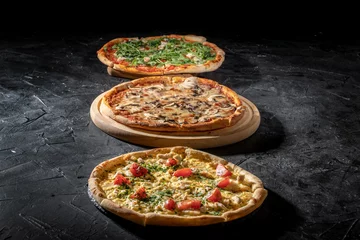 Fotobehang Three delicious traditional italian pizza, vegetables, ingredients on a dark background. Pizza menu © Andrii
