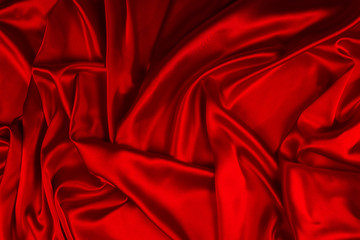 Red silk or satin luxury fabric texture can use as abstract background. Top view.