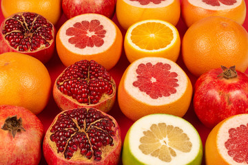 Grapefruit, orange, pomegranate, citrus sweetie on red background.
