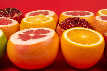 Grapefruit, orange, pomegranate, citrus sweetie on red background.