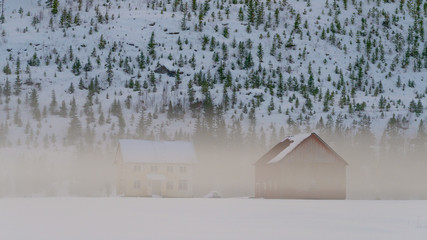 An old farm in Norway in typical valley mist during winter