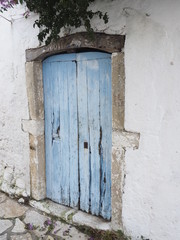 old blue wooden door in white wall greek village
