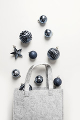 Obraz na płótnie Canvas Christmas felt winter bag with classic blue balls on grey background. Xmas shopping concept. View from above, flat lay. Trendy color, Pantone 2020. Vertical orientation.