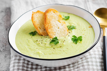Homemade broccoli cream soup with croutons in white bowl on grey background. Healthy vegetarian food. Vegan menu.