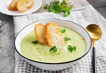 Homemade broccoli cream soup with croutons in white bowl on grey background. Healthy vegetarian food. Vegan menu.