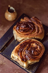 Brioche with chocolate on a wooden stand and a sauce-boat in rustic style