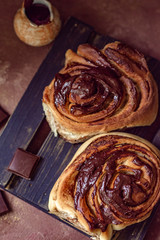 Brioche with chocolate on a wooden stand and a sauceboat in a rustic rustic style vertical arrangement