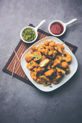 Gobi pakora or Phoolgobi pakoda made using fresh cauliflower dipped chickpea batter and then fried in oil. served with tomato ketchup and mint chutney. selective focus