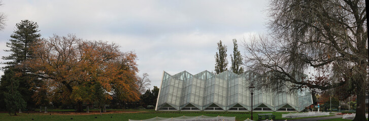 Obraz premium panoramic image of a large modern tropical garden glasshouse in an autumn botanical gardens in old town Ballarat, rural Victoria, Australia