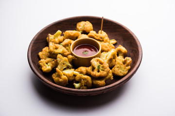 Gobi pakora or Phoolgobi pakoda made using fresh cauliflower dipped chickpea batter and then fried in oil. served with tomato ketchup and mint chutney. selective focus