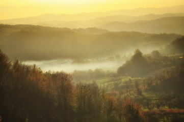Beautiful autumn mountain in the sunset mist. Glowing sunset on the autumn forest. Lens flare effect. Soft focus.