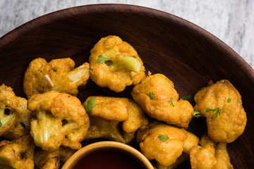 Gobi pakora or Phoolgobi pakoda made using fresh cauliflower dipped chickpea batter and then fried in oil. served with tomato ketchup and mint chutney. selective focus