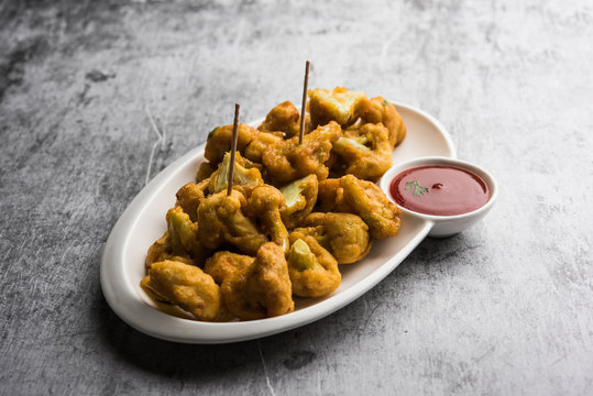 Gobi pakora or Phoolgobi pakoda made using fresh cauliflower dipped chickpea batter and then fried in oil. served with tomato ketchup and mint chutney. selective focus